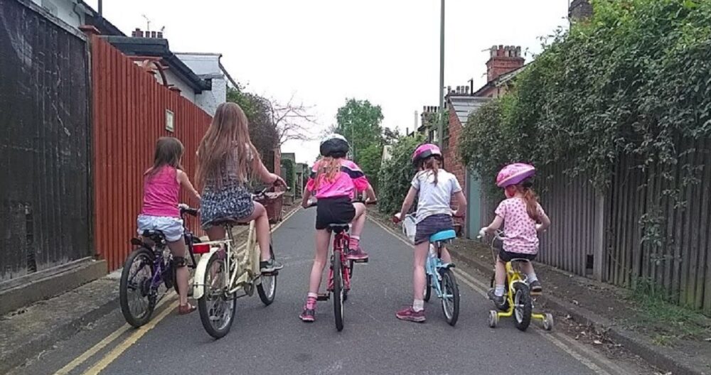 Bikes for girls: a row of five little girls of different ages, mounted on bicycles, seen from behind