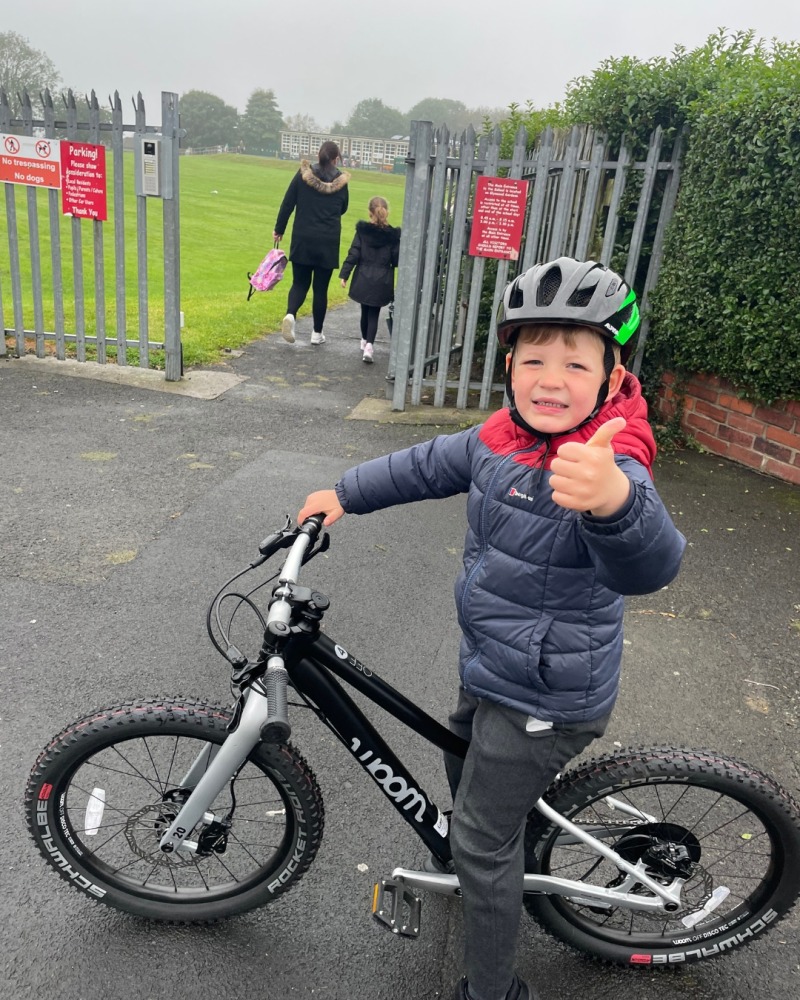 Boy standing on bicycle in front of school gates
