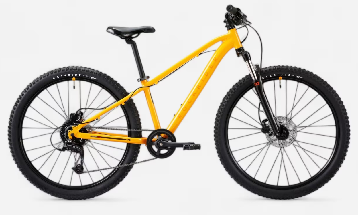 The Rockrider EXPL900 26 Mountain Bike shown here with a yellow frame and chunky 2.2" wheel tyres is one of the best 26 inch kids mountain bikes available in the UK