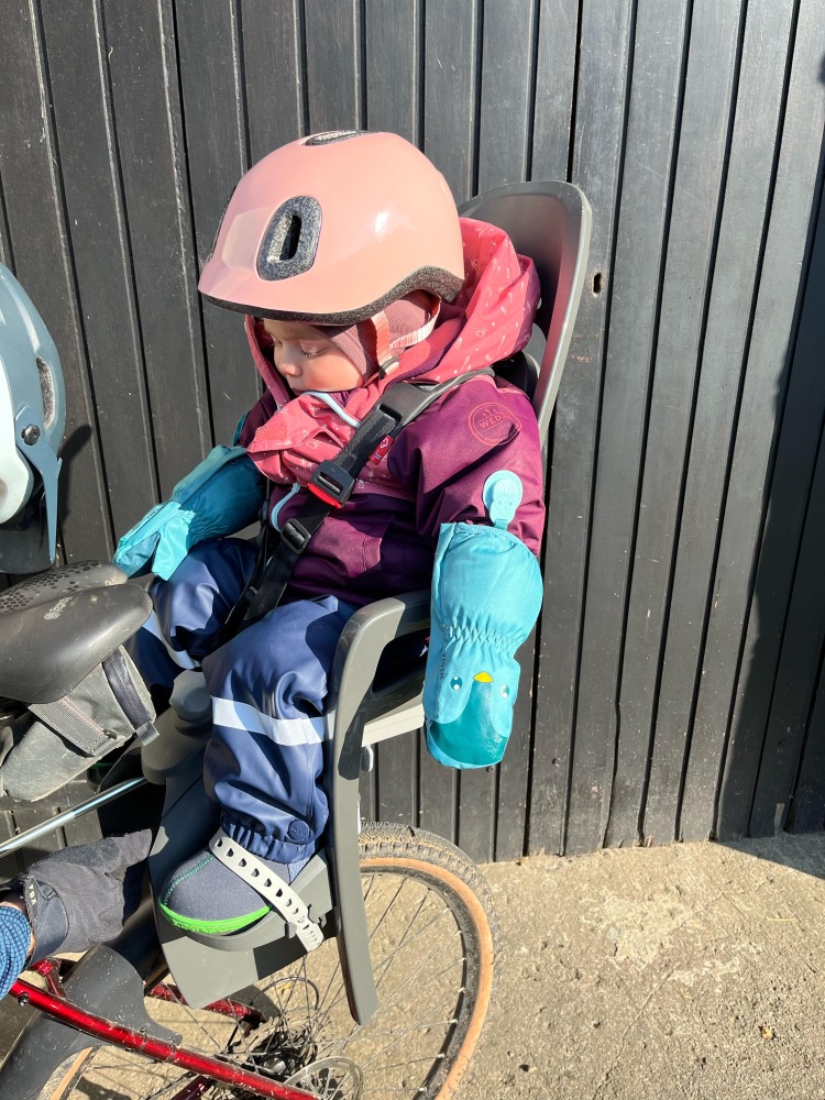 a little girl in a pink helmet in her Hamax Zenith Relax rear seat on her mums bike