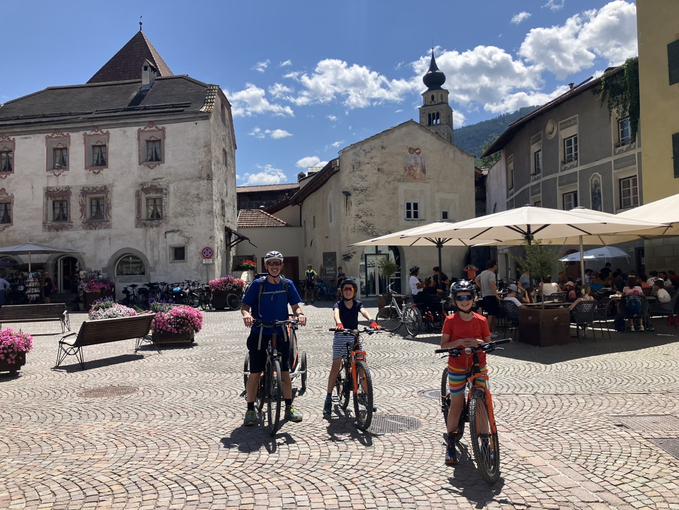 family cycling routes in Austria & italy: Bea's family and their bikes in the middle of a medieval square