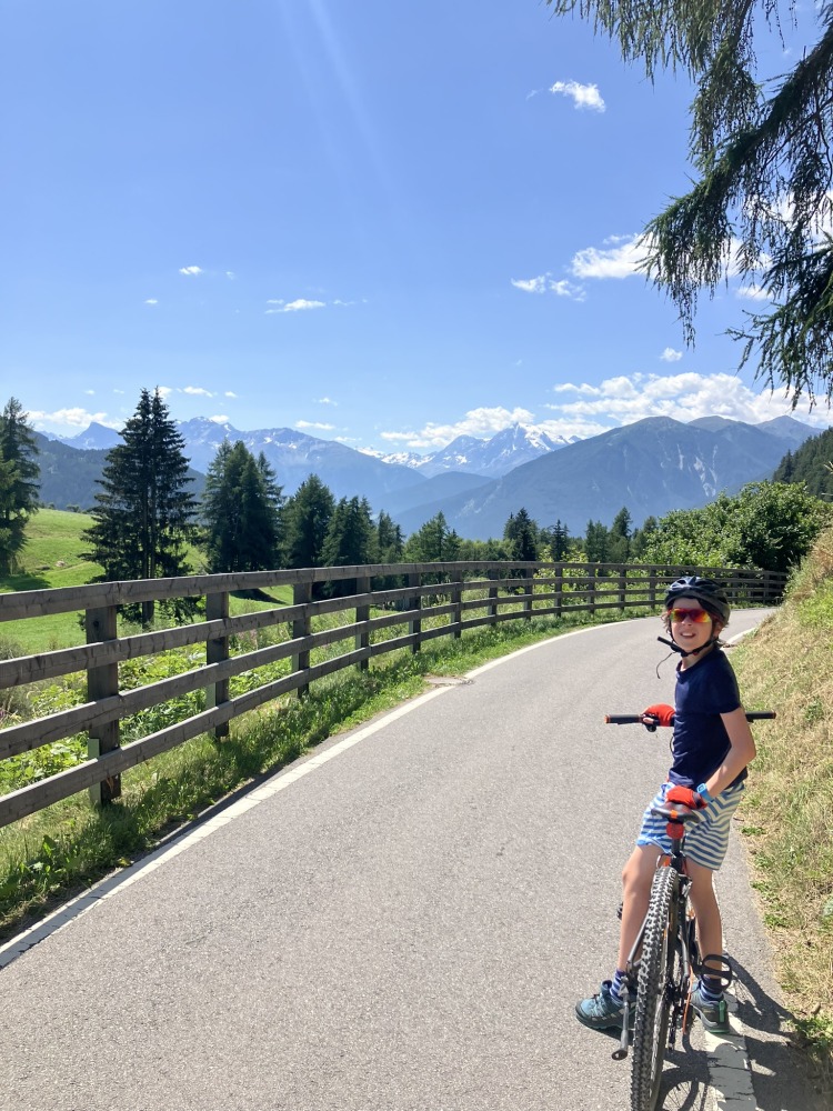 family cycling routes in Austria & italy: One of Bea Searle's children stopped on their bike on a clear, smooth tarmac path