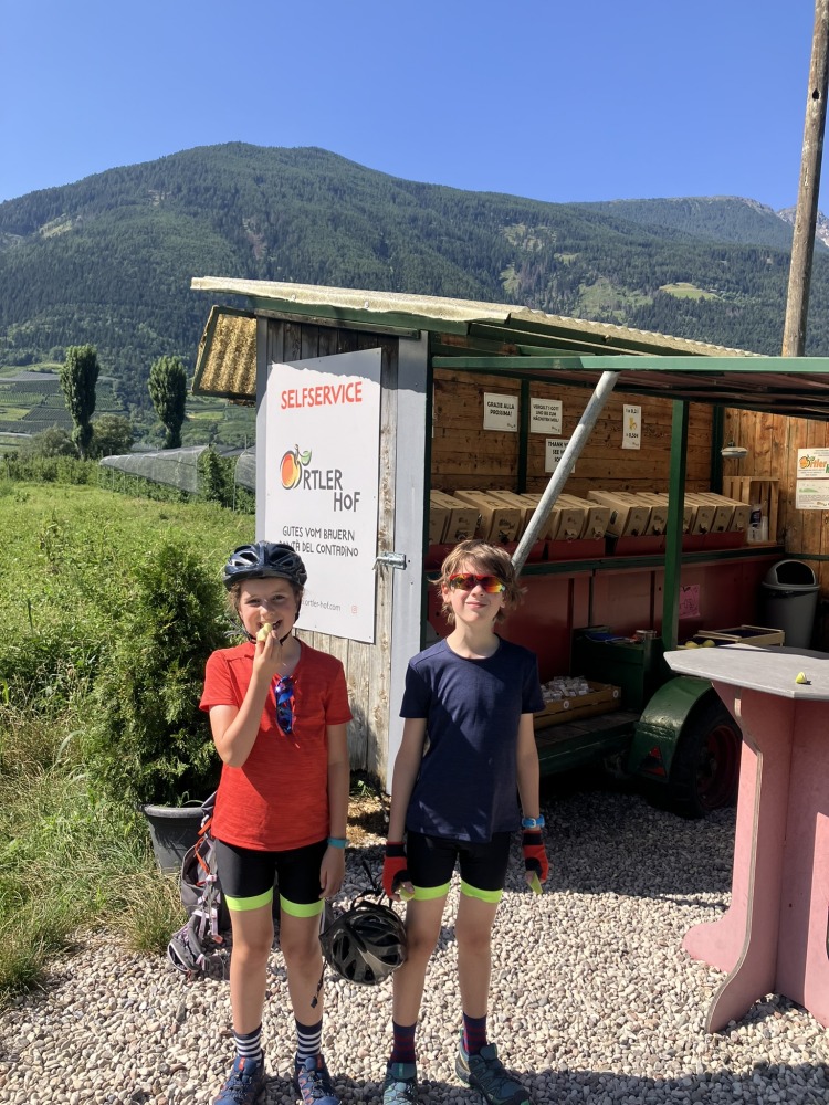 family cycling routes in Austria & italy: Bea Searle's two children eating apples in front of a little shack