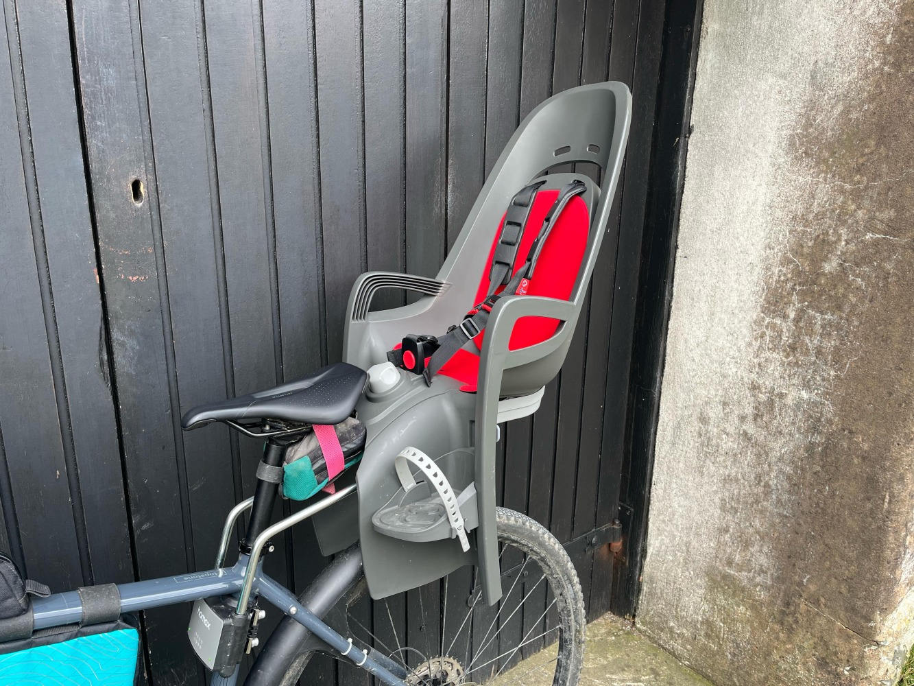 grey and red Hamax seat photographed side on by a garage door