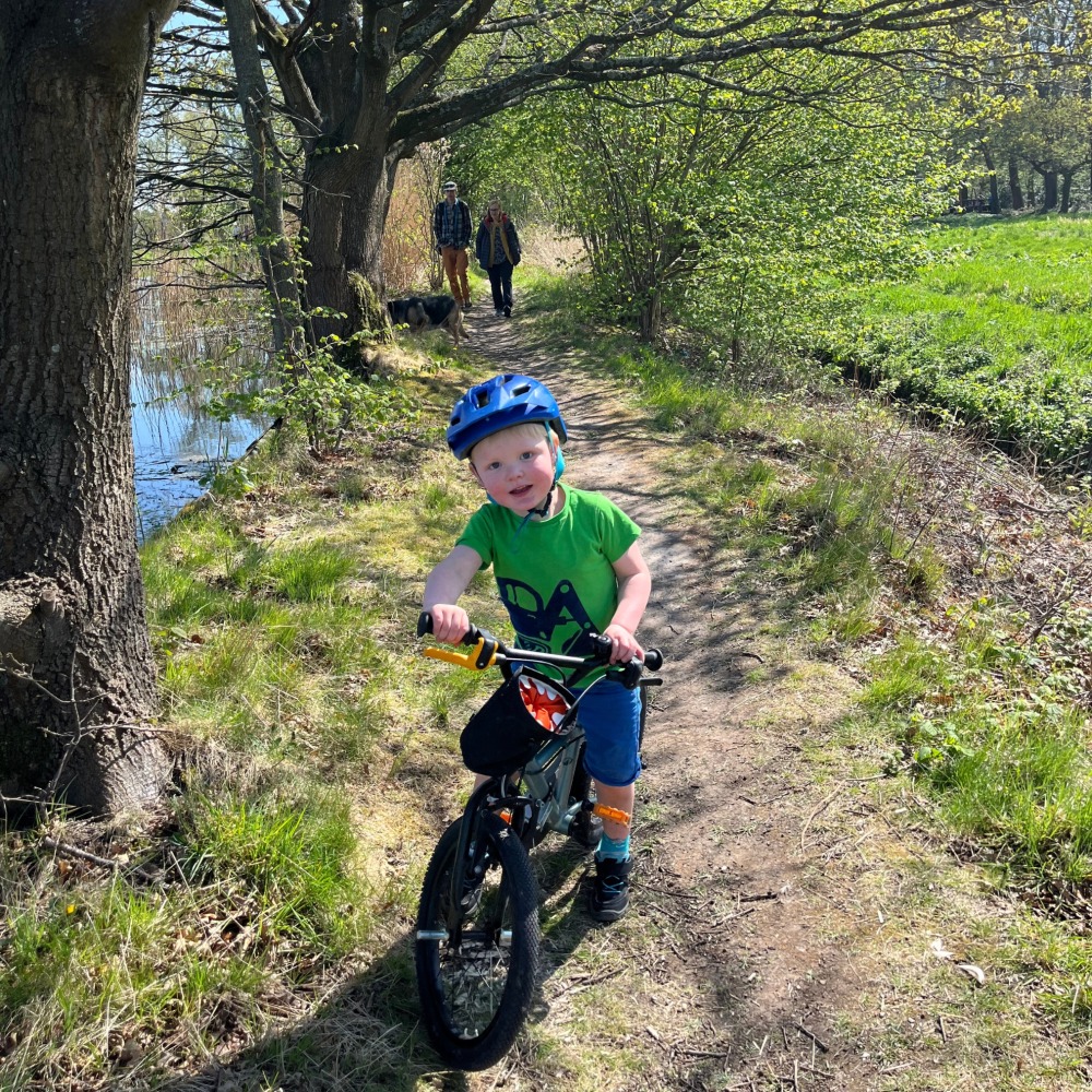 BTWIN 16 Discover 900 review- a smiling 3 year old riding on a muddy path next to the river