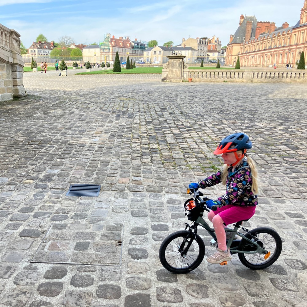 BTWIN 16 Discover 900 review- a girl in a flowry jumper and blue helmet riding on a cobbled street