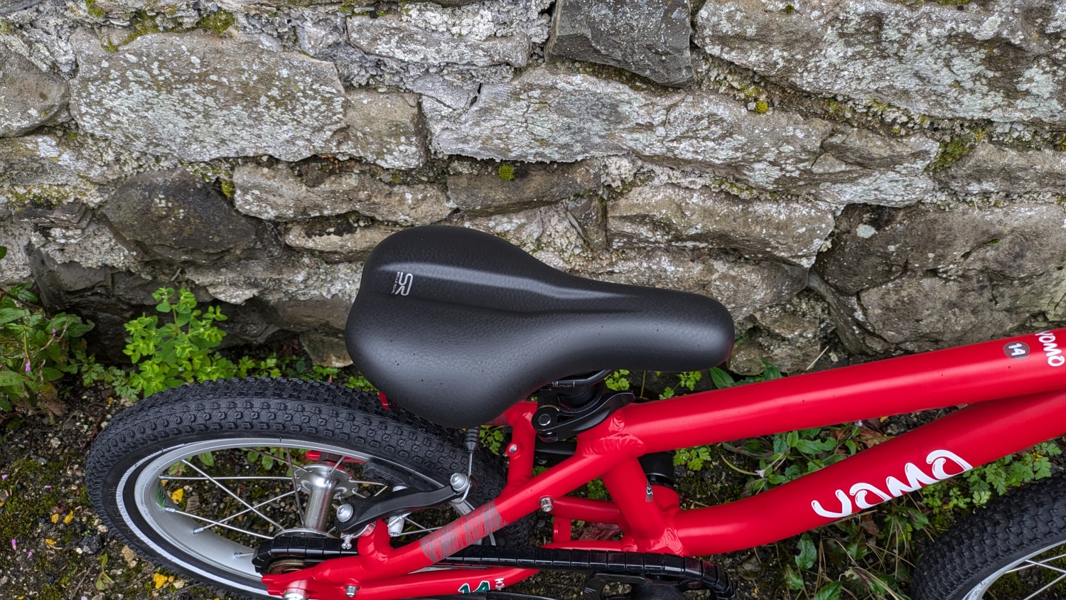YOMO 14 review: the red bike leant against a wall- close up of the saddle