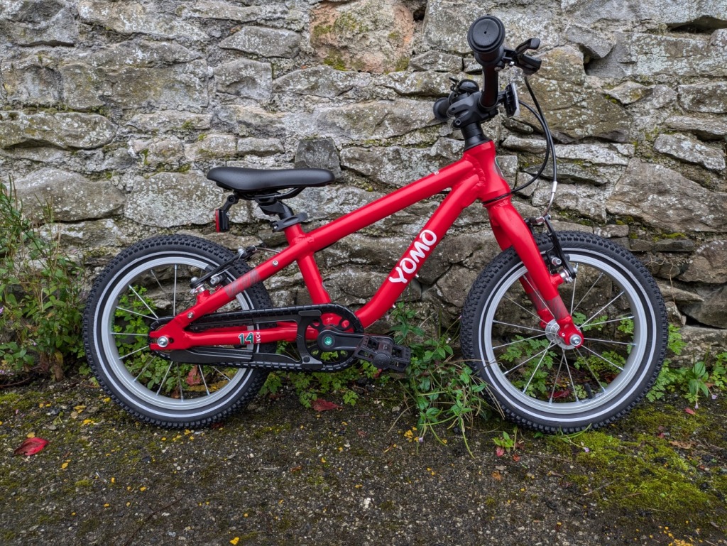 best 14 inch kids bikes: the red yomo bike leant against a wall