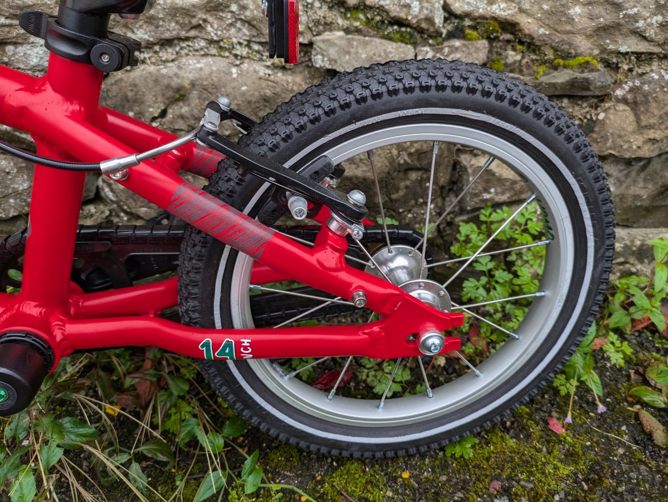 YOMO 14 review: the red bike leant against a wall- close up of the rear wheel