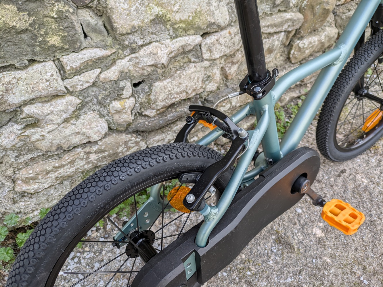 A photo of the BTWIN 16” Discover 900 leant against a wall for its review- close up of the back brake
