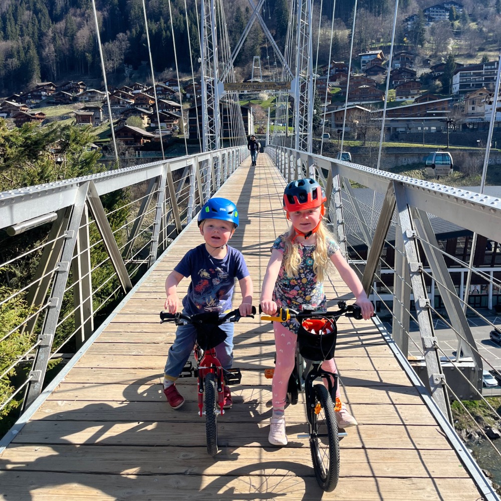 Harry and robin, two children side by sides on their bikes on a bridge on a sunny day