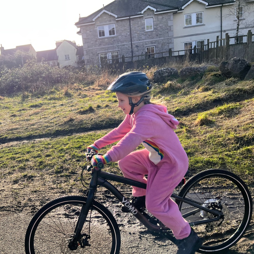 YOMO 24 review- a girl in a pink fluffy onesie is riding her yomo 24 bike