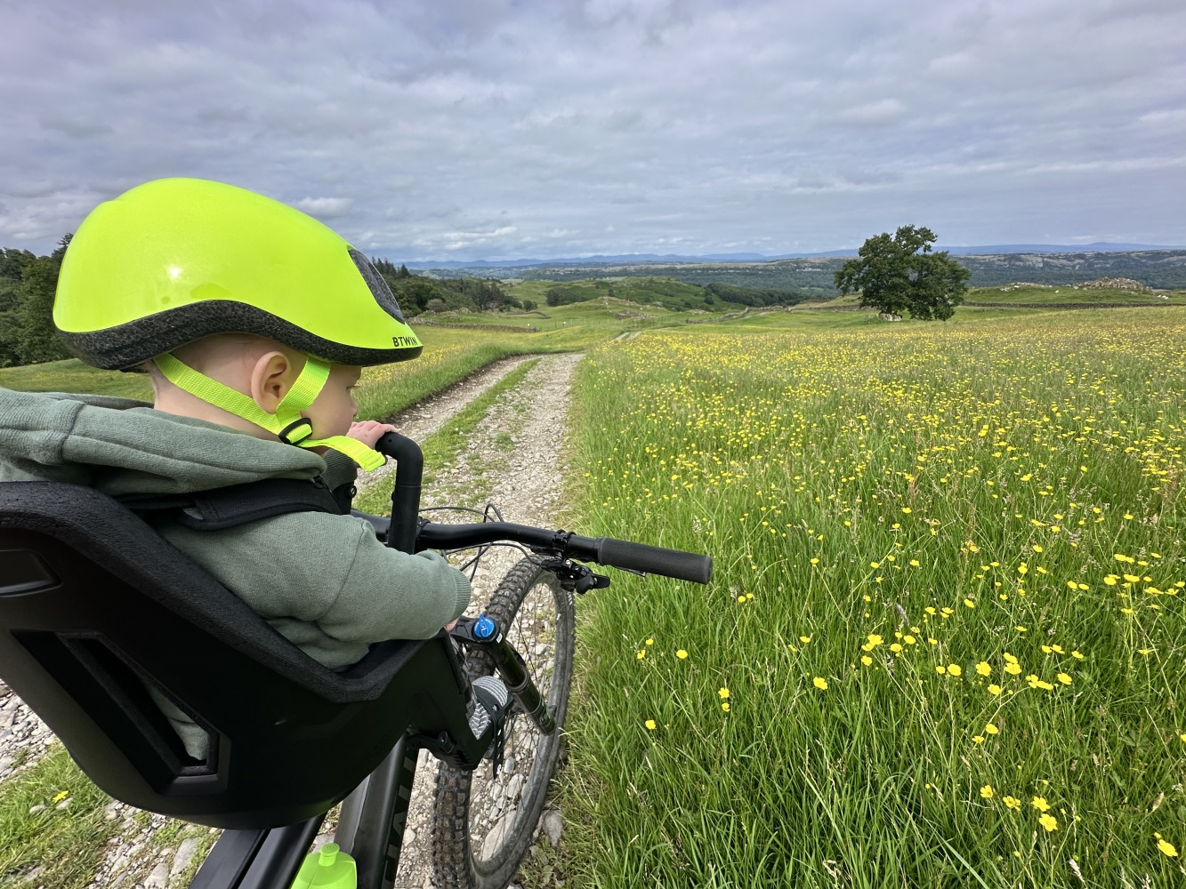 kids ride shotgun pro evo baby seat review- a photos of a little boy in a yellow helmet smiling on a bike ride with his mum