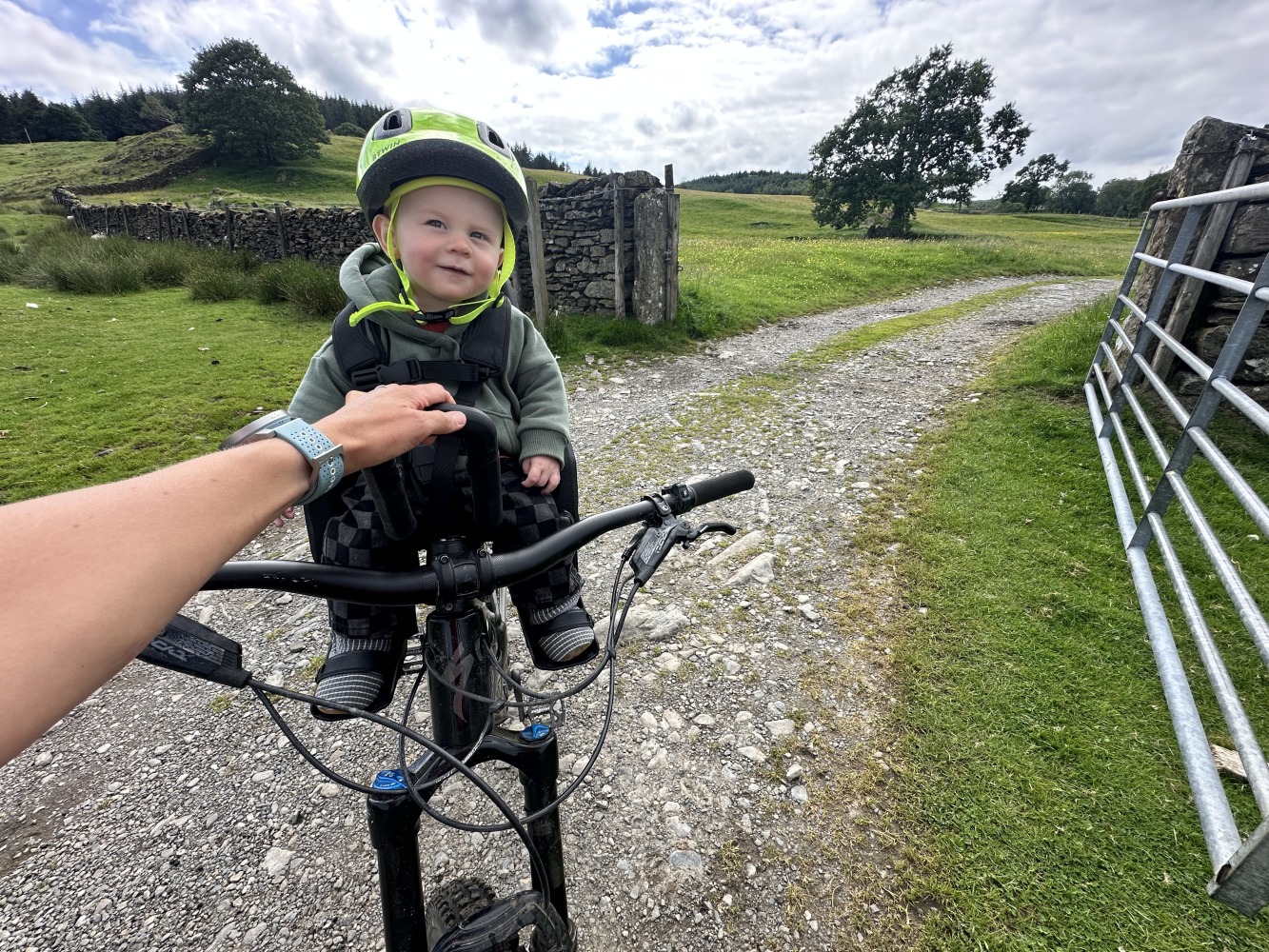 kids ride shotgun pro evo baby seat review- a photos of a little boy in a yellow helmet smiling on a bike ride with his mum