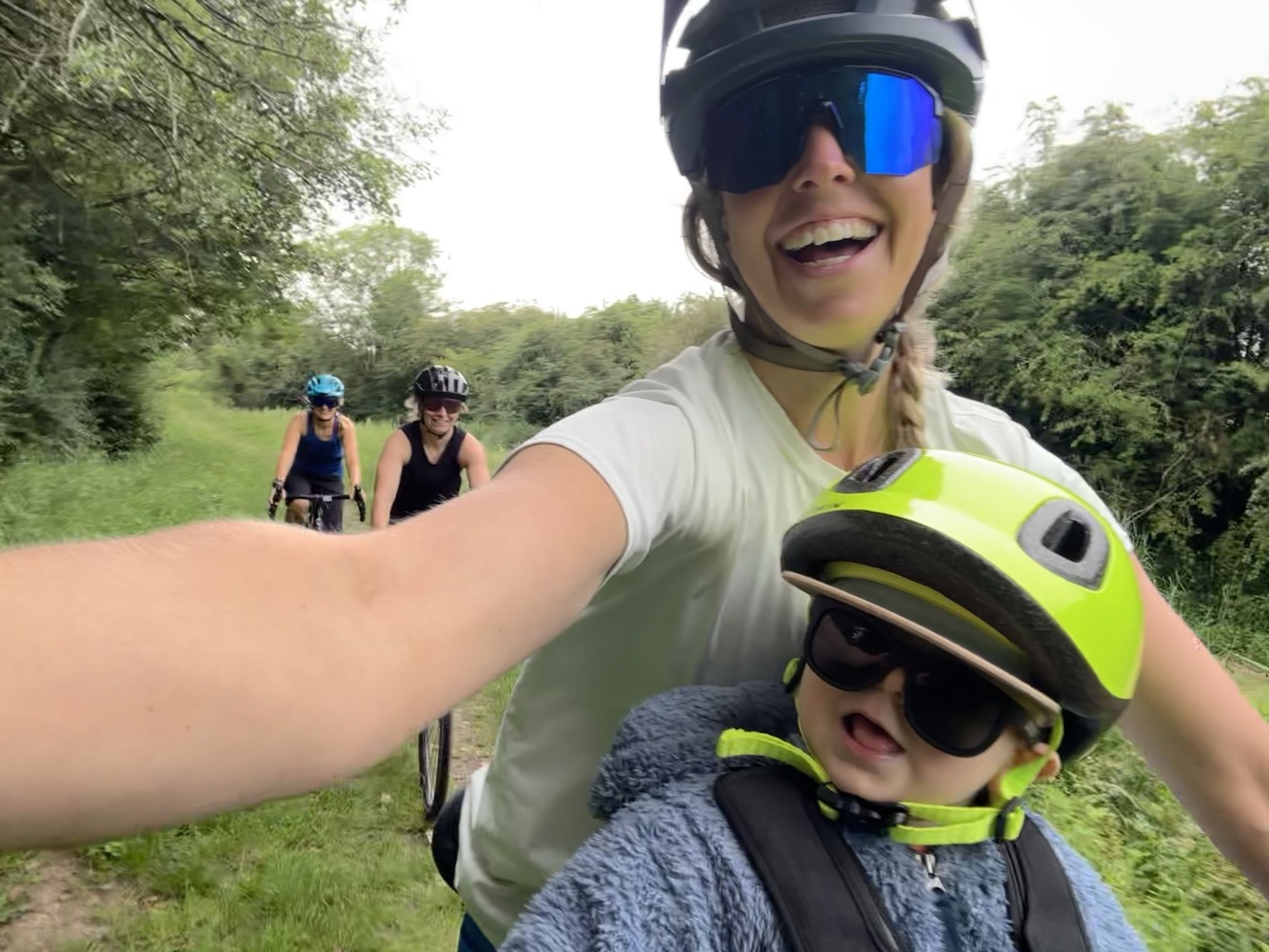 kids ride shotgun pro evo baby seat review- a photos of a little boy in a yellow helmet smiling on a bike ride with his mum and her friends