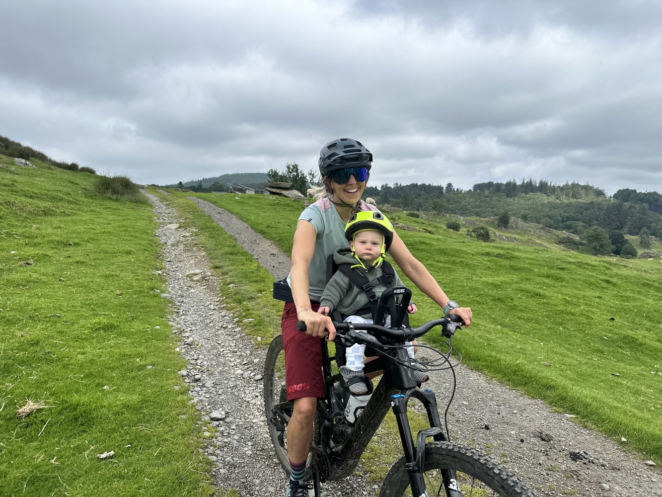 kids ride shotgun pro evo baby seat review- a photos of a little boy in a yellow helmet smiling on a bike ride with his mum