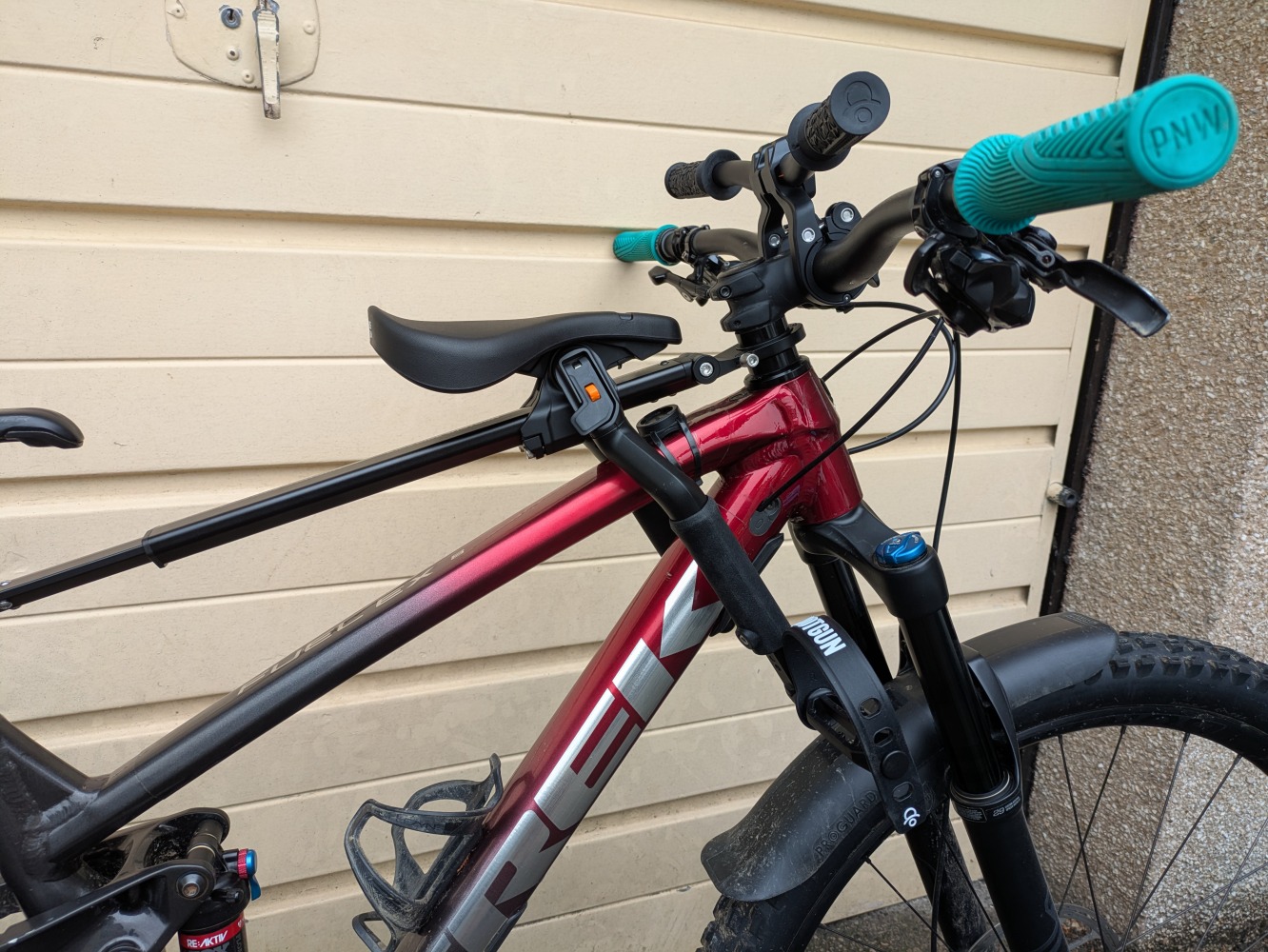 A Kids Ride Shotgun Pro Evo seat, in toddler mode mounted to a red trek MTB with pro handlebars