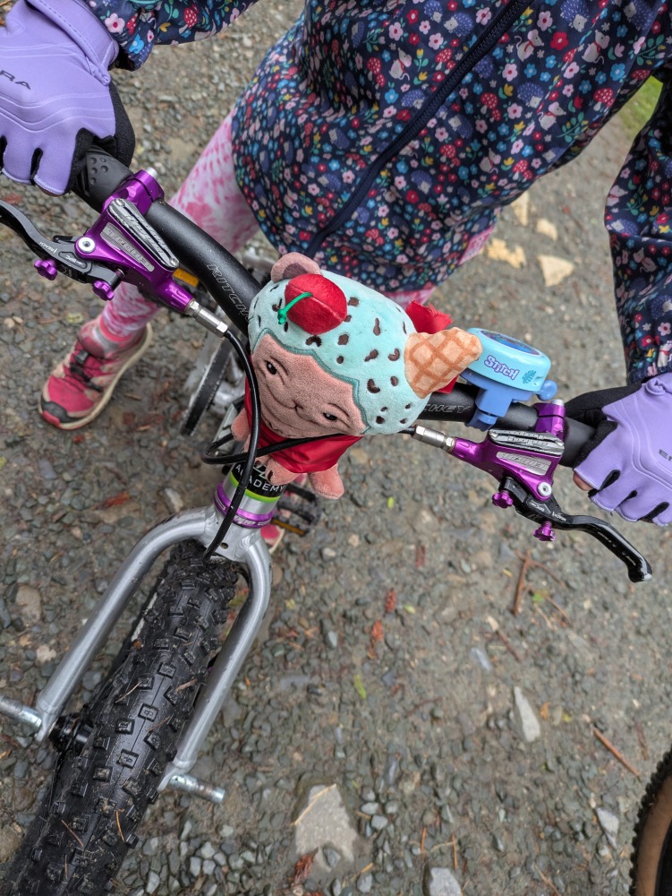 Best bike accessories for kids: Looking down on a child's handlebars with a fun plushie accessory and bell