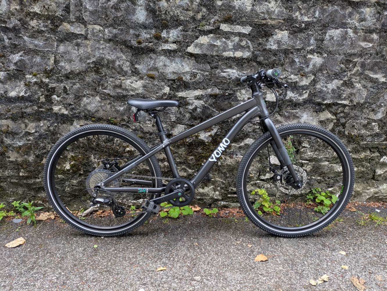 YOMO 24 review- the grey bike leant against a stone wall