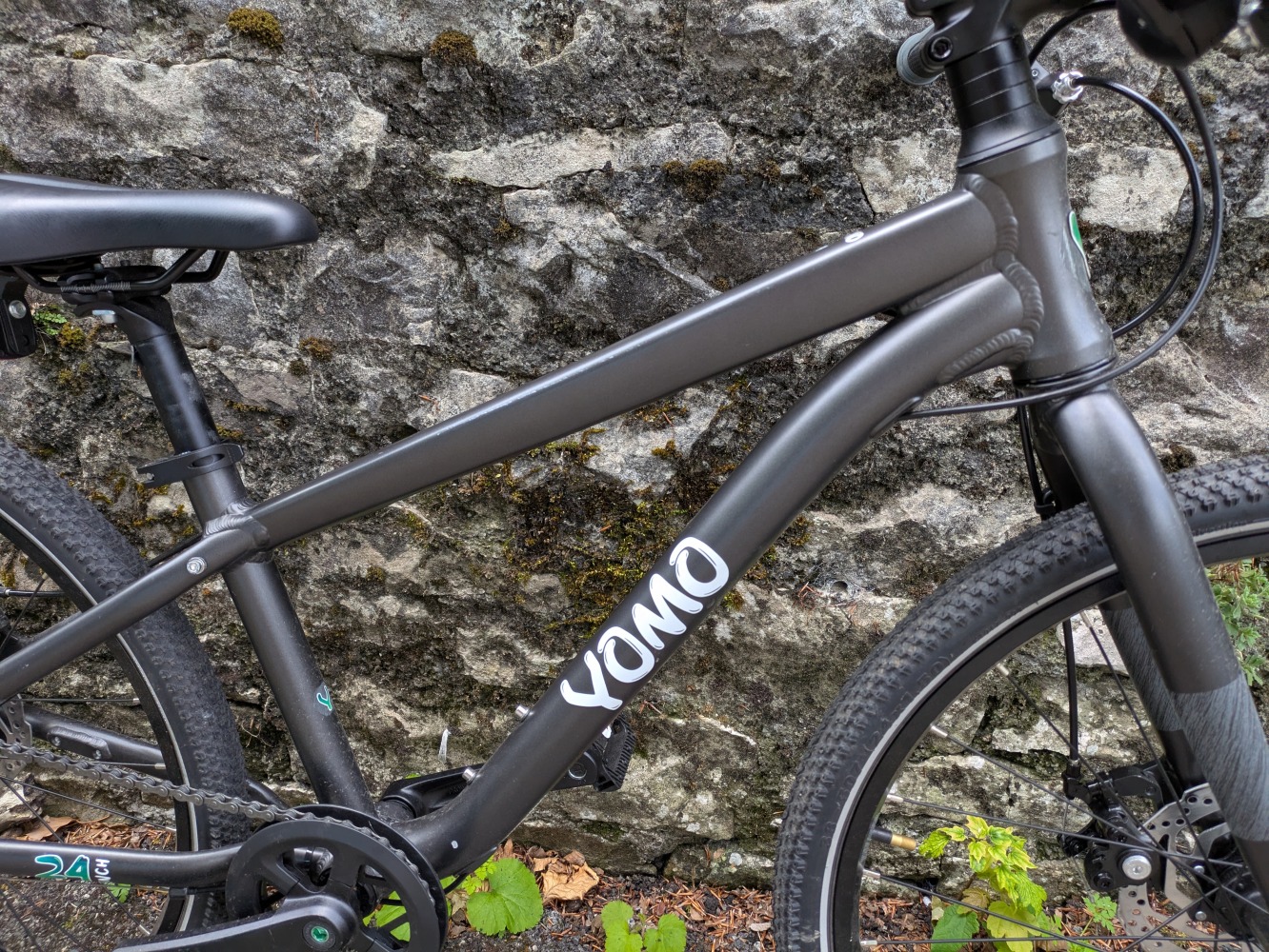 YOMO 24 review- the grey bike leant against a stone wall