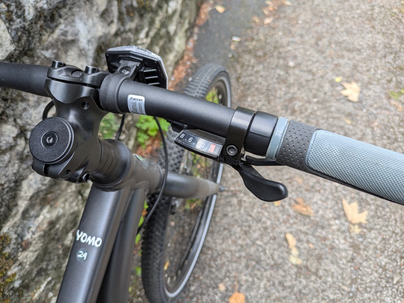 YOMO 24 review- the grey bike leant against a stone wall, close up of the gear shifter