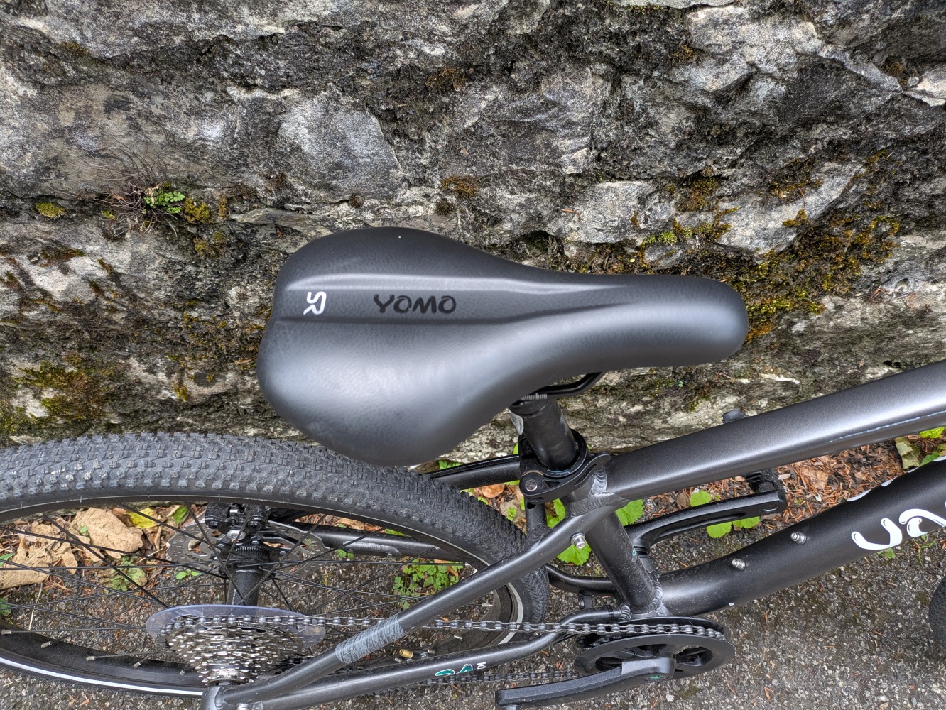 YOMO 24 review- the grey bike leant against a stone wall, close up of the saddle
