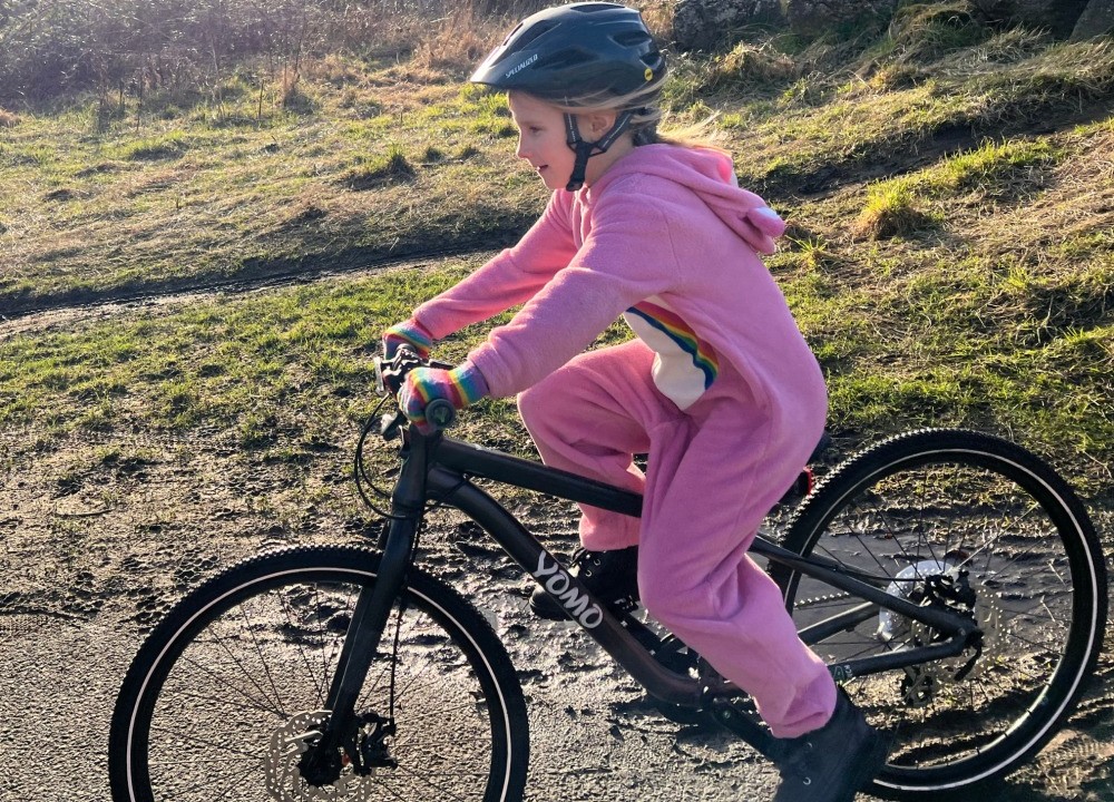 YOMO 24 review- a girl in a pink fluffy onesie is riding her yomo 24 bike