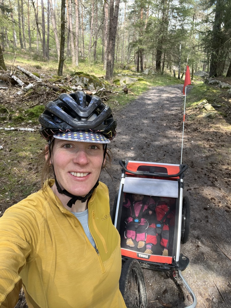 A selfie of Hetty Kingston wearing a bike helmet and showing her twins in the trailer behind her