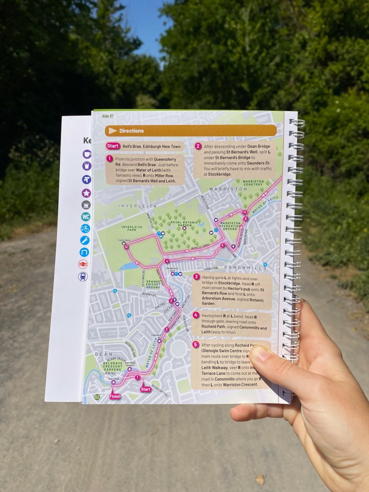 a hand holding the cycling london guidebook