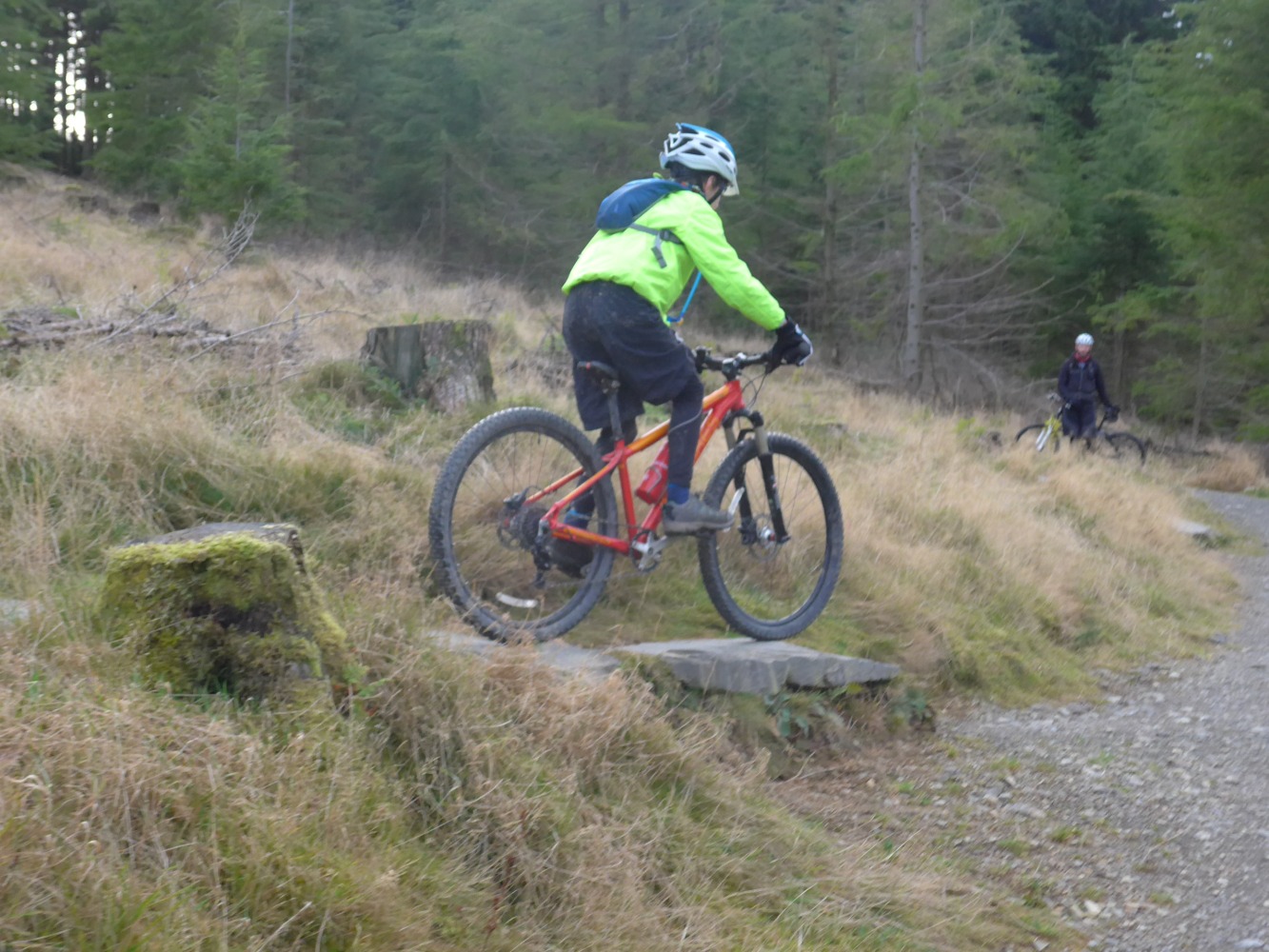 A boy seen from behind about to ride his mountain bike over a drop off
