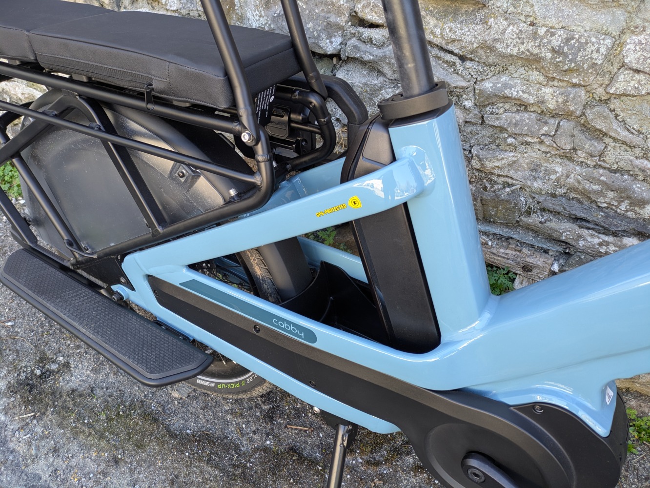 Two children sitting on a Urban Arrow Family cargo bike, looking away and waving