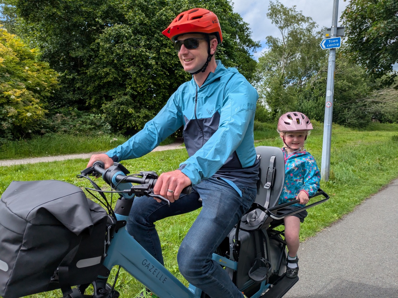 Gazelle Cabby review- a dad in a blue coat and orange with his daughter in a blue jacket and pink helmet and school dress riding the gazelle cabby