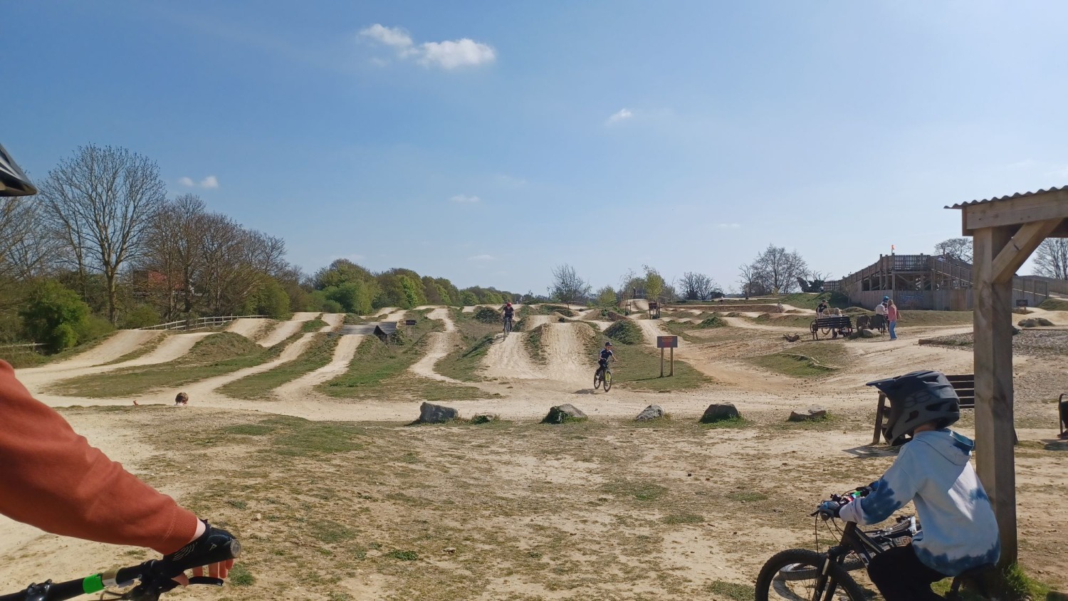 A huge dirt track pump track, with a couple of kids in full face helmets in the foreground