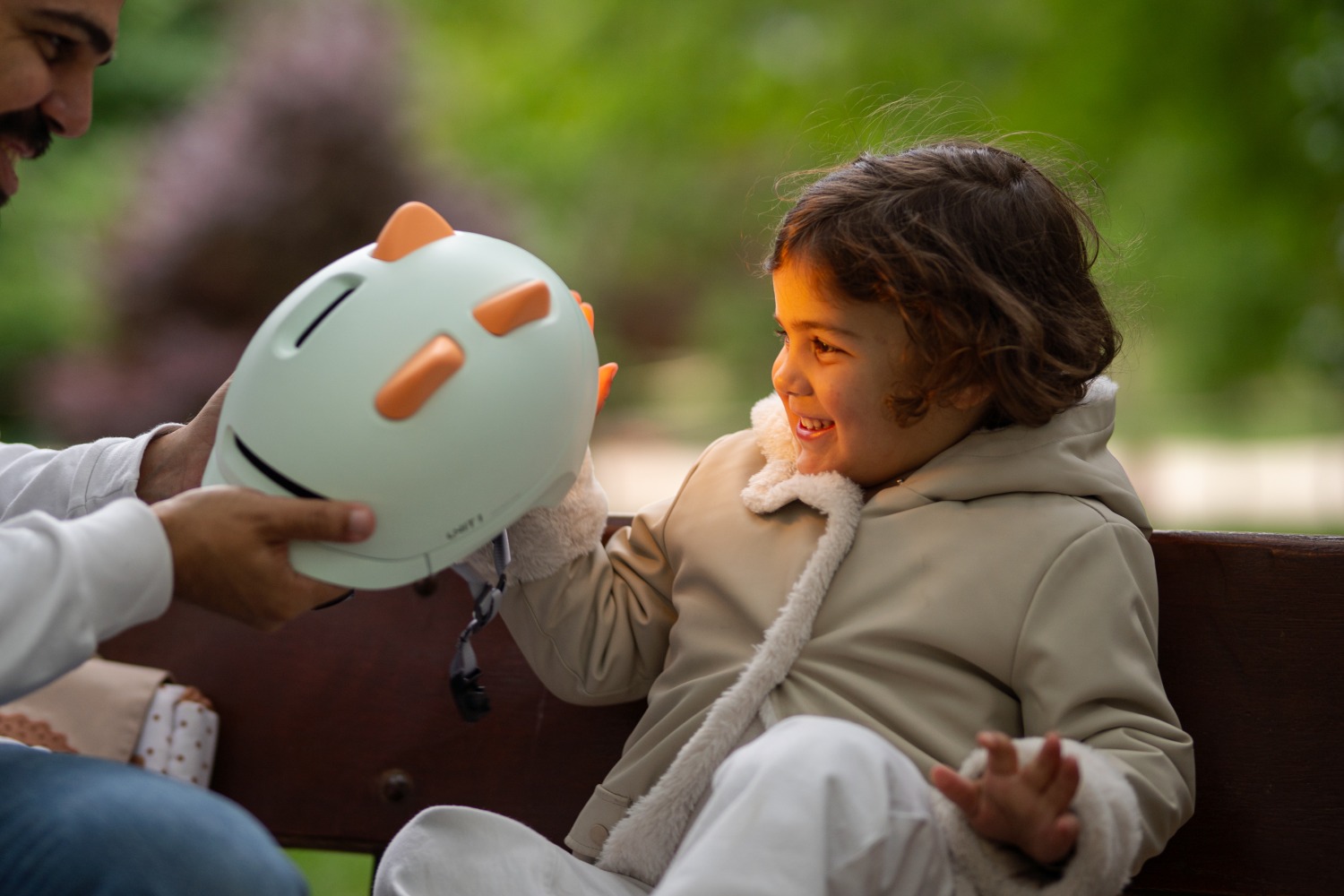 Girl sat on a bench with her dad loving playing with the silicone inserts on her SPARKY helmet
