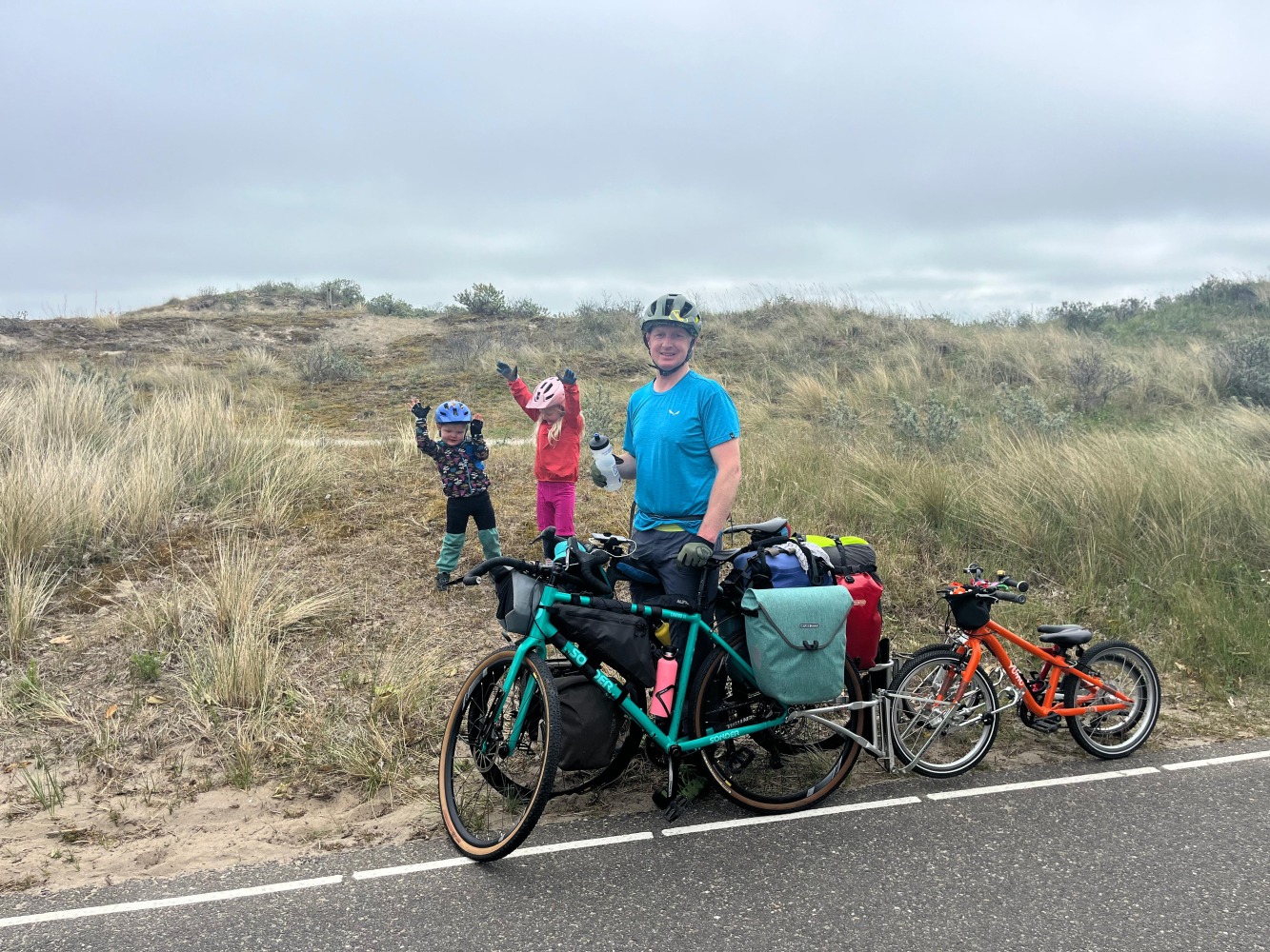 A familly cycling touring, stopped with their bikes leant up and the kids dancing