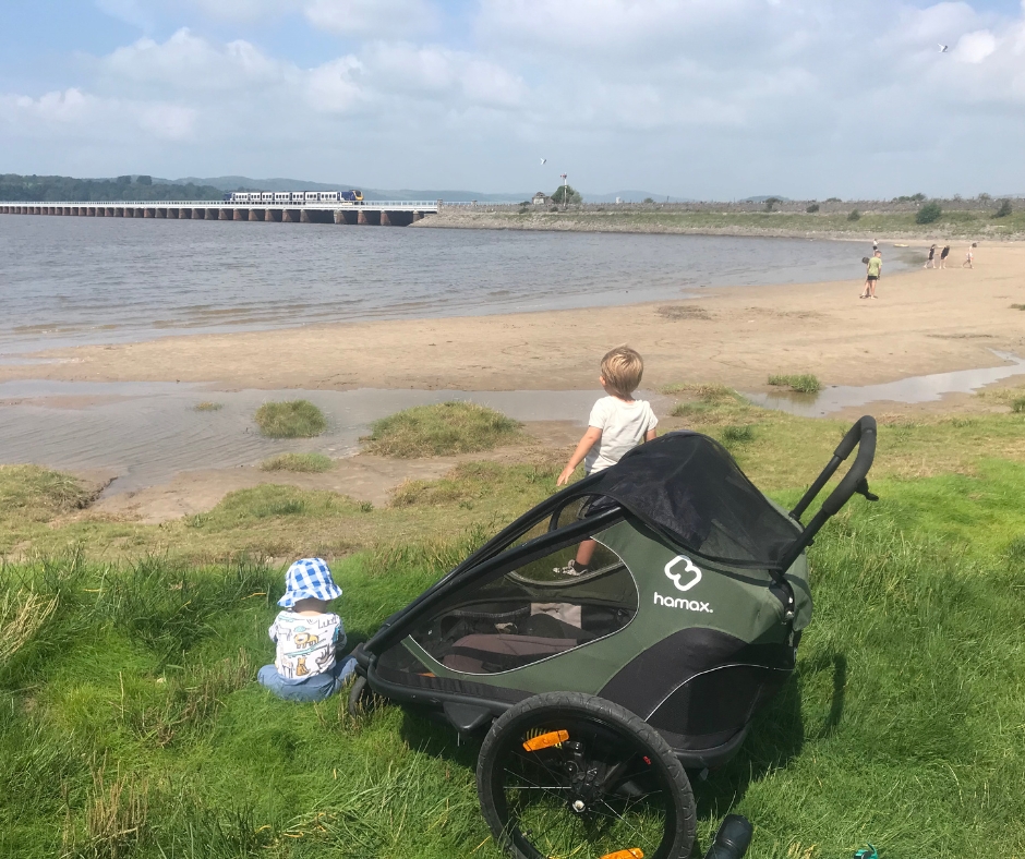 two children playing at the beach with the Hamax Outback trailer