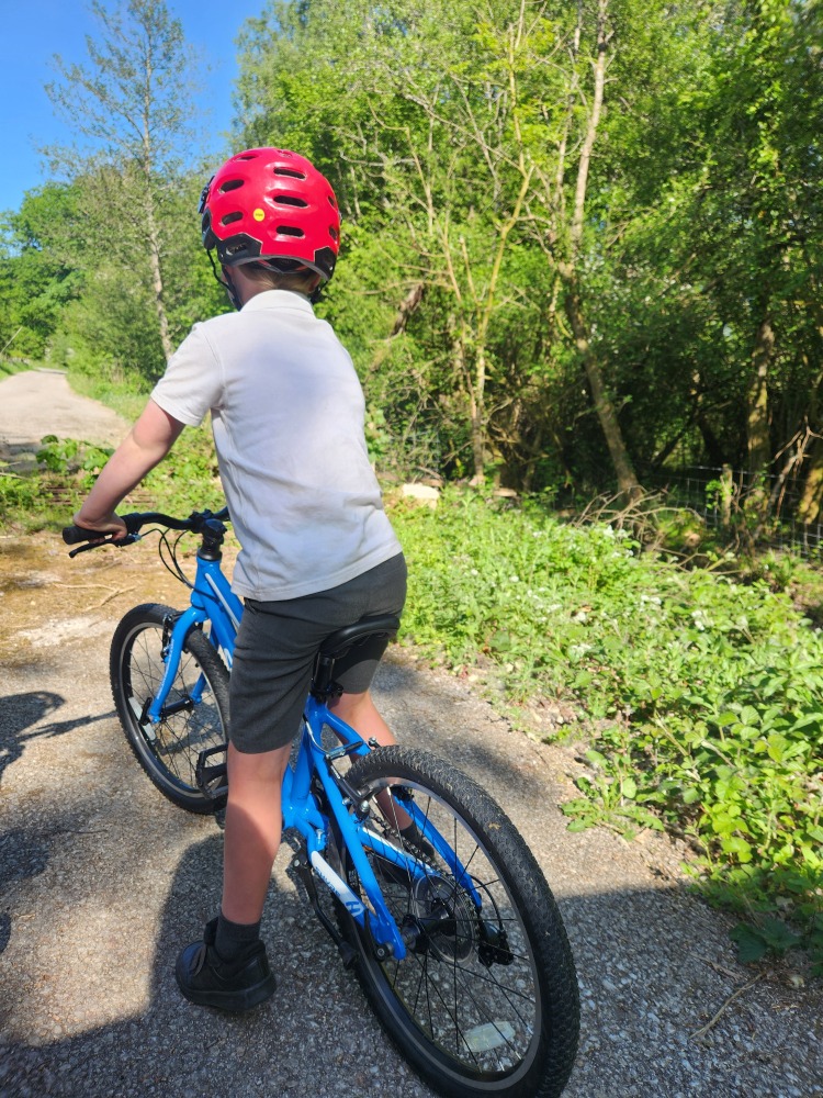 Shyre Hopton 20 review: A boy in his school uniform seen from behind, standing over the bike