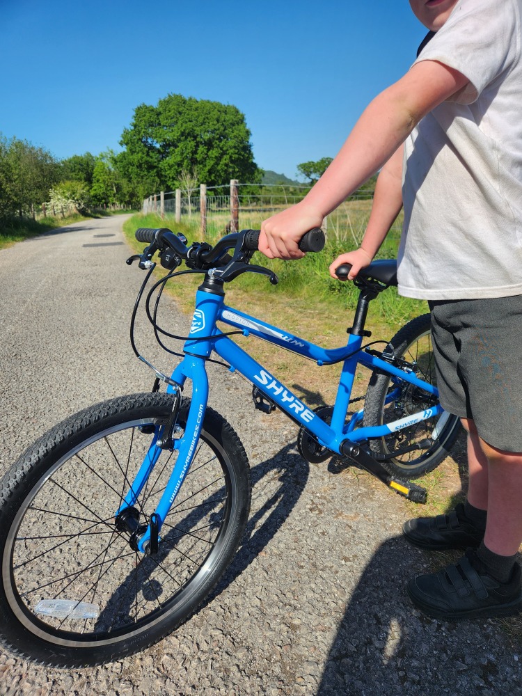 Shyre Hopton 20 review: A boy in his school uniform standing next to the Shyre Bike, holding it by the saddle and handlebar