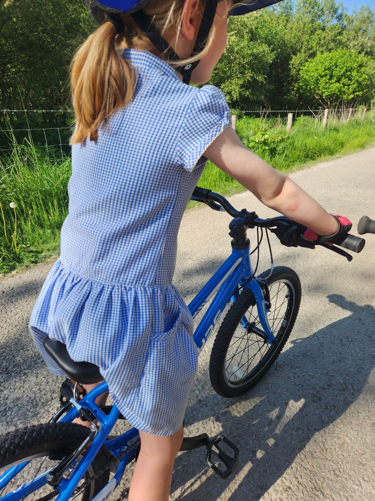 Shyre Hopton 20 review: A little girl in a school dress cycling the Shyre bike along a tarmac path