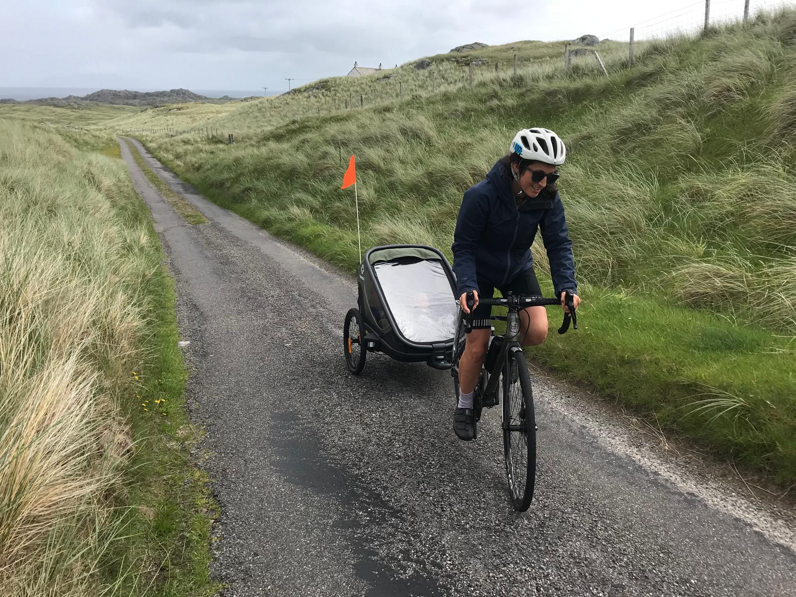a mum riding uphill with the Hamax Outback trailer