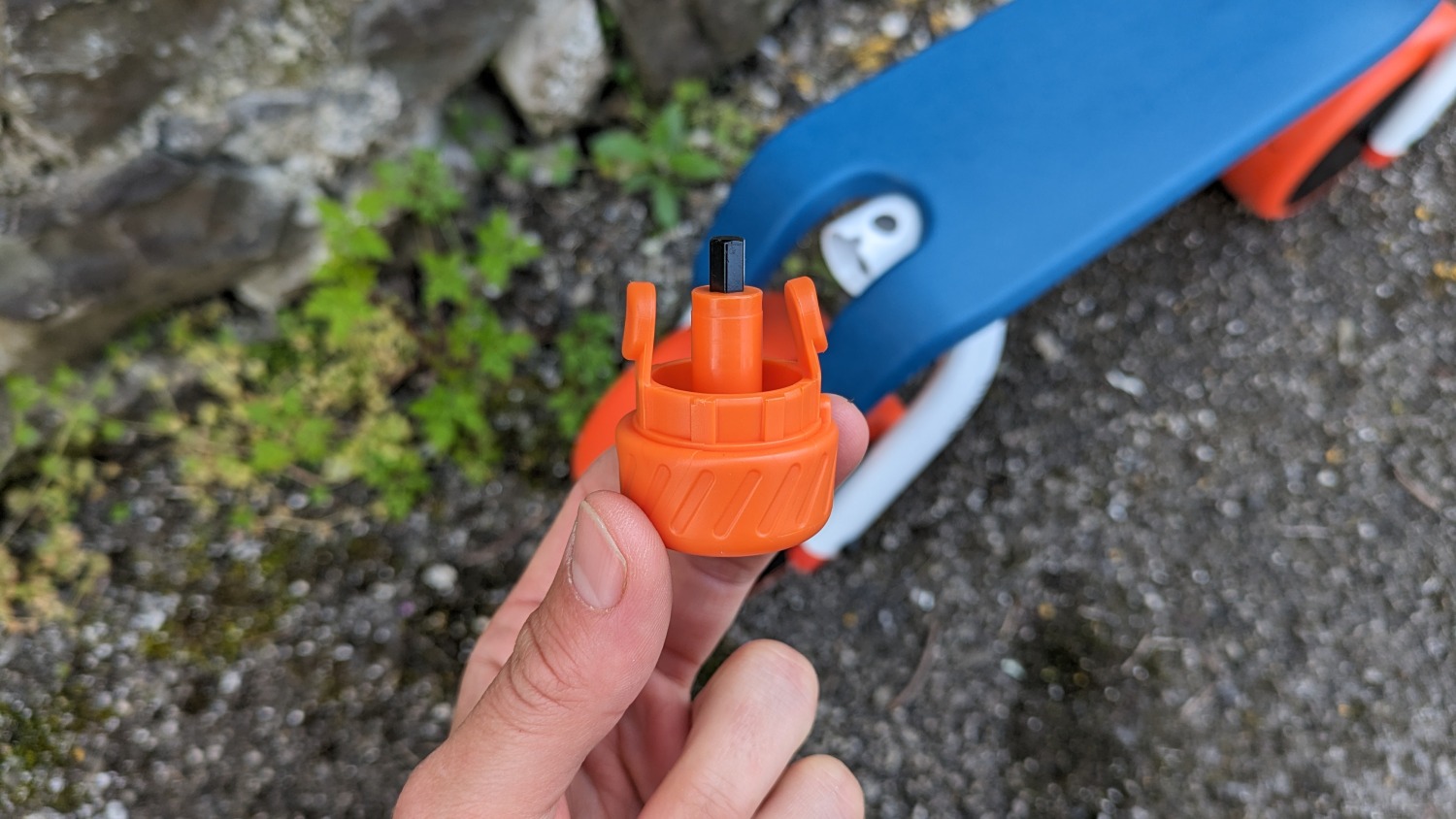 Btwin Convertible 2-in-1 Ride-On to Balance Bike, a white, orange and blue bike, close up of the allen key