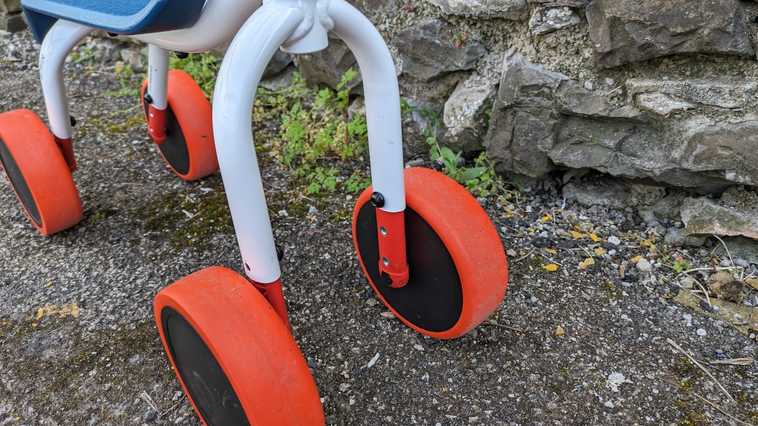 Btwin Convertible 2-in-1 Ride-On to Balance Bike, a white, orange and blue bike- close up of the adjustable height wheels
