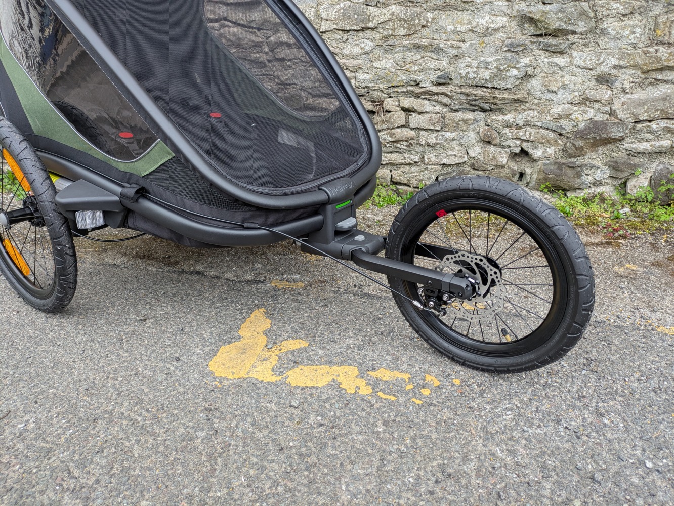 A green Hamax Outback double trailer- a close up of the running wheel