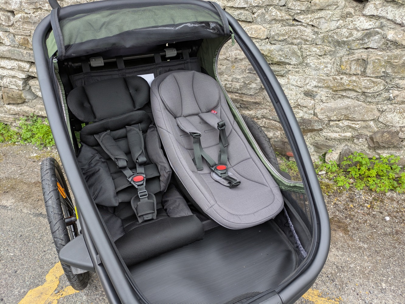 A green Hamax Outback double trailer- a close up of the two seats and baby insert