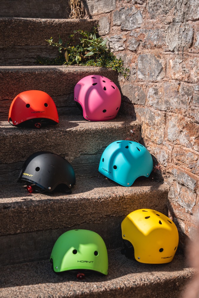 Six Hornit AIRO helmets in different colours, arranged on a set of stone steps in the sun