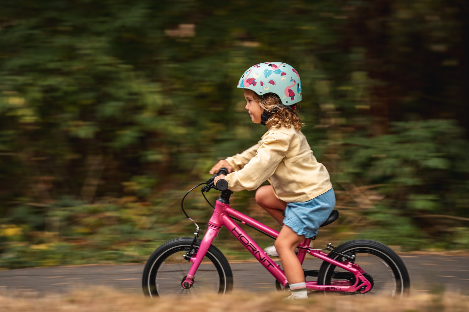 A young child riding the new Hornit HERO 14 on a gravel path
