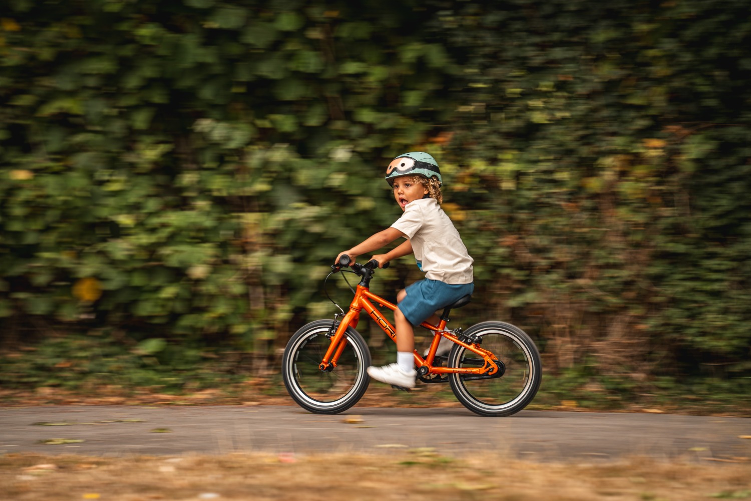 A young child riding the new Hornit HERO 16 on a gravel path
