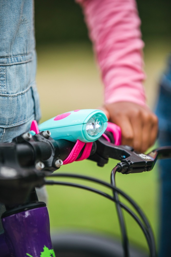 A close up of a brightly coloured Hornit MINI bike light mounted to a handlebar
