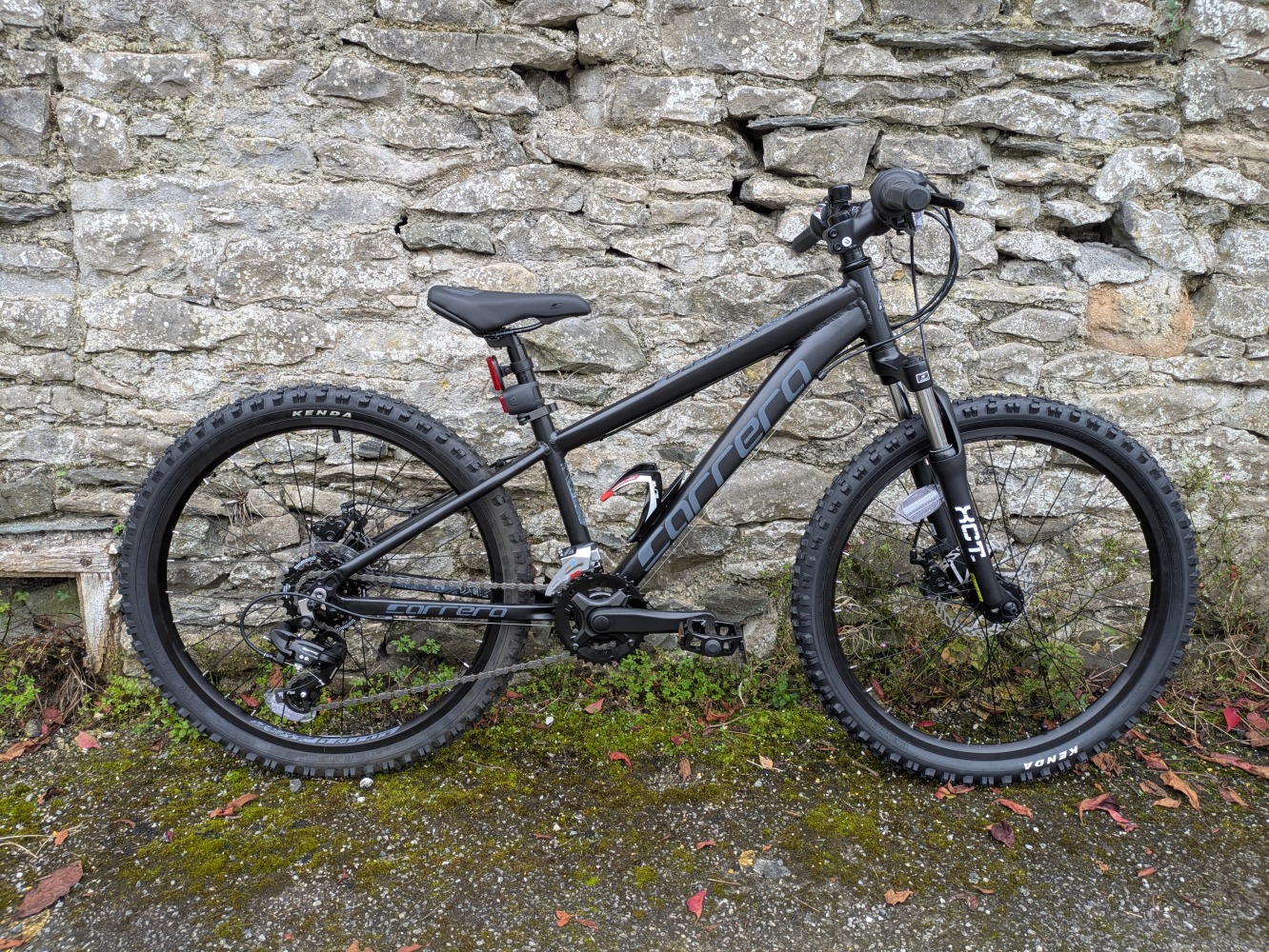 Carrera kids mountain bike from Halfords leaning up against a wall