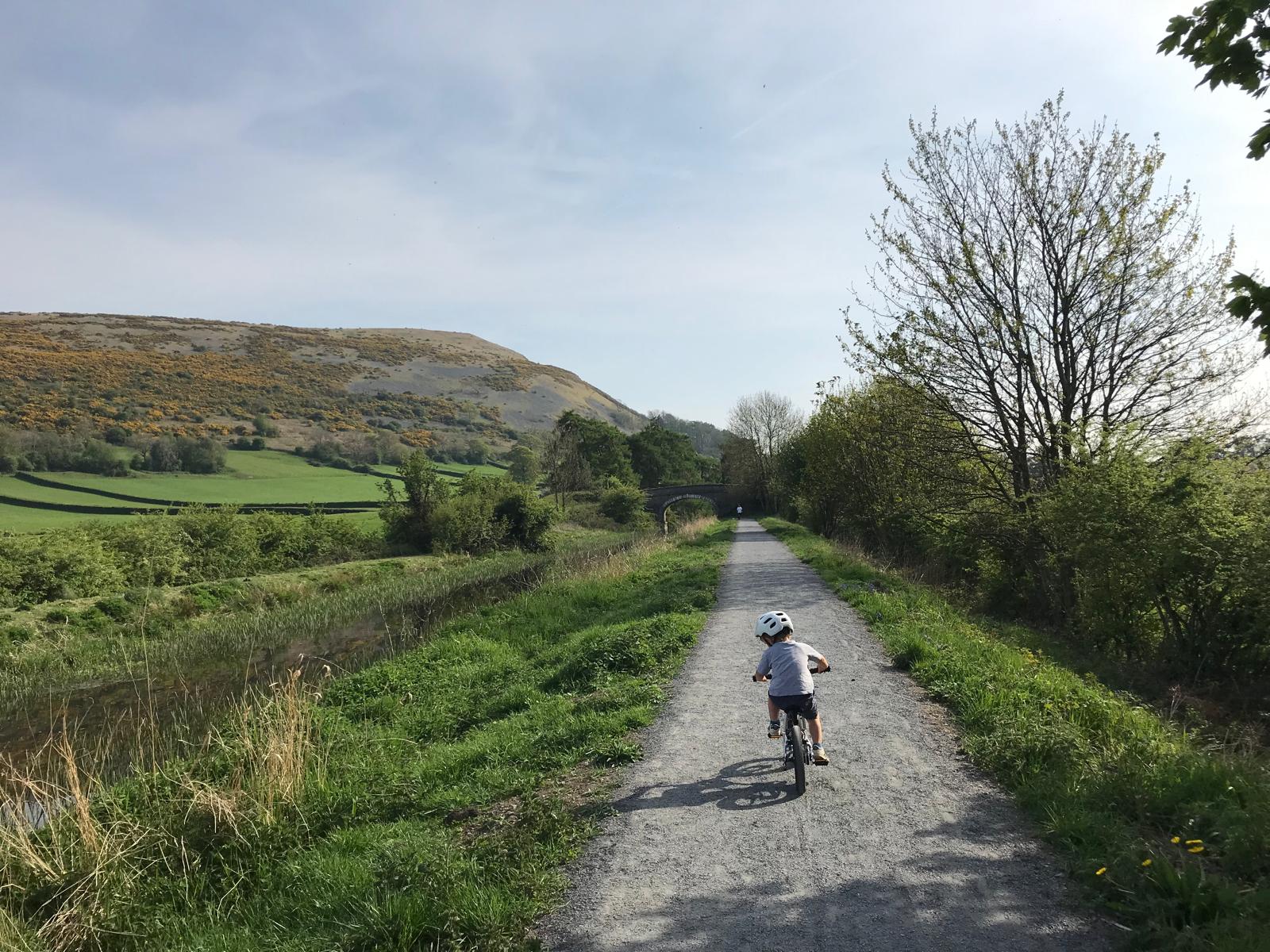 A little boy riding the Early Rider Belter 14 on a sunny day on a gravel path